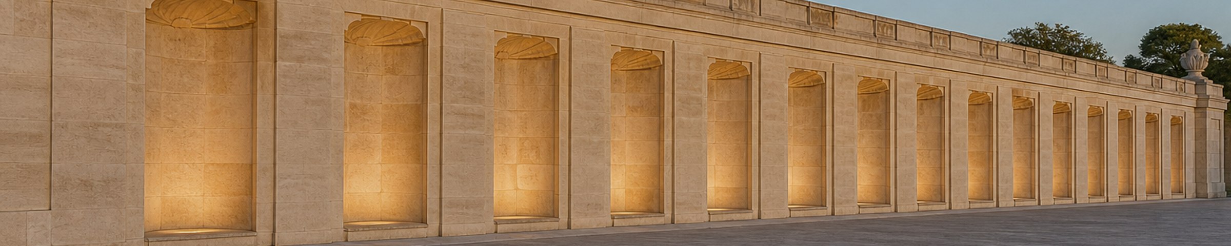 Lit stone alcoves along a limestone wall at dusk.